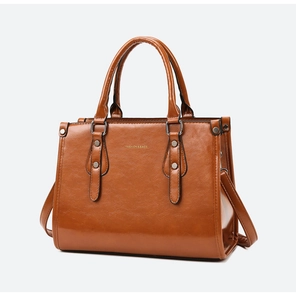Détail du cabas en cuir verni marron avec rivets dorés et lettrage du logo