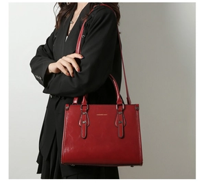 Détail d'un sac à main en cuir verni rouge avec logo métallique poli et rivets ronds