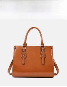 Vue détaillée du sac à main en cuir verni marron avec clous dorés et marquage