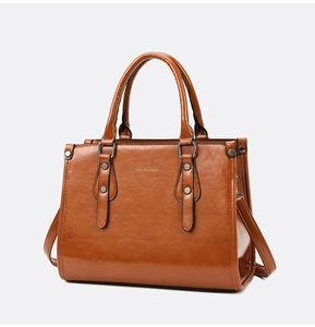 Détail du sac en cuir verni marron avec rivets dorés et inscription du logo
