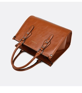 Détail d'un sac à main en cuir verni marron avec logo doré et rivets métalliques