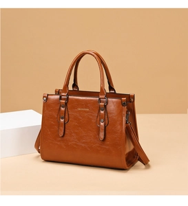 Détails du sac cabas en cuir verni marron avec logo doré élégant et rivets décoratifs