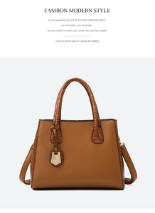 Detail of tan tote bag featuring embossed crocodile pattern accents and pebble leather texture