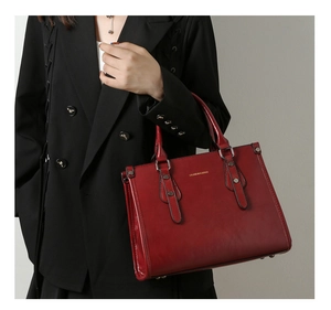 Détail du sac cabas en cuir verni bordeaux avec rivets argentés et logo embossé