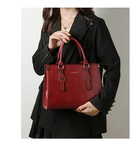 Détail du sac cabas en cuir verni bordeaux avec rivets et logo fashion élégant