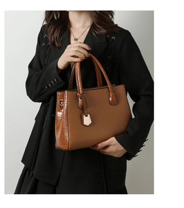 Close-up of brown crocodile embossed leather handbag styled with a black blazer jacket