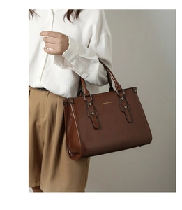 Détail d'un sac cabas en cuir verni marron avec clous métalliques et poignées