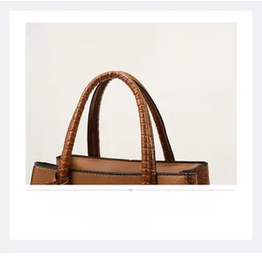 Detailed view of brown crocodile-embossed handle and pebbled leather texture on bag