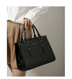 Détail du sac cabas en cuir verni noir avec logo doré et finitions métalliques chic
