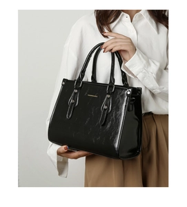 Gros plan du sac cabas en cuir verni noir avec finition brillante et détails argentés