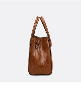 Close-up of brown crocodile pattern handbag showing detailed embossed leather and D-ring