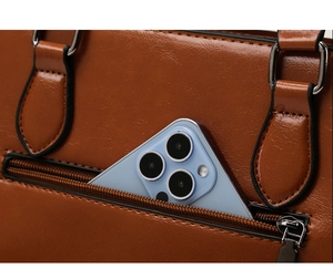 Détail du sac en cuir verni marron montrant la poche extérieure zippée avec un smartphone