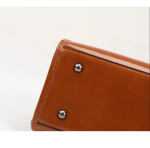 Détail du fond de sac en cuir verni marron avec clous de protection et coutures fines