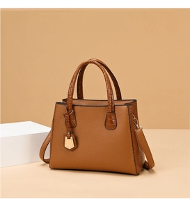 Detail of brown faux leather bag with litchi grain and crocodile texture accents