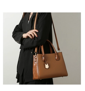 Detail of brown crocodile embossed tote bag with gold hardware shown on shoulder