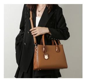 Detail of brown crocodile pattern shoulder bag with metallic charms and thin straps