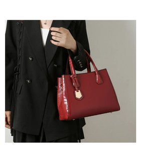 Detail of red tote bag with crocodile texture worn with a black blazer