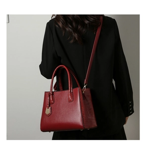 Detailed view of crocodile texture on deep red leather bag with gold hardware accents