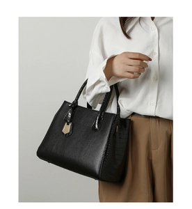 Detail of black tote bag featuring lychee grain leather and embossed crocodile texture