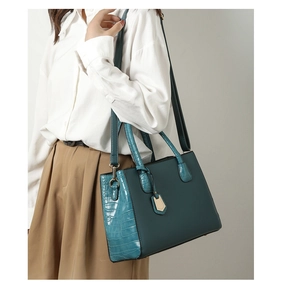 Detail of teal crocodile embossed pattern and smooth matte leather on women's handbag