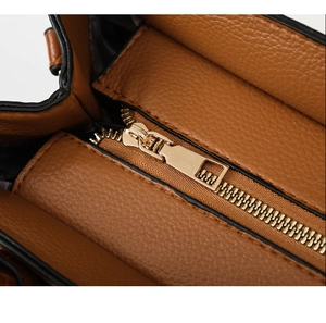 Close-up of golden zipper and lychee pattern leather on brown shoulder bag detail