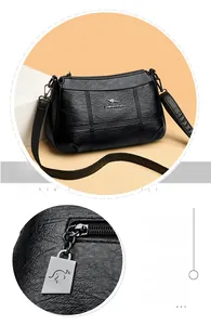 Détail de la texture cuir noir et du logo kangourou doré sur le sac à bandoulière