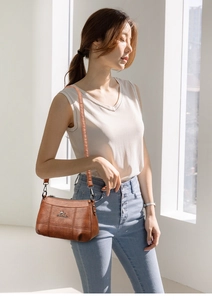 Détail de la texture du sac en cuir marron avec logo kangourou et finitions argentées