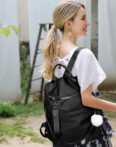 Détail d'un sac à dos en nylon noir avec rivets métalliques et pompon blanc décoratif