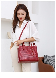 Close-up of red patent leather tote bag with woven texture and gold hardware details