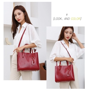 Model wearing a large red woven texture handbag with golden hardware and shoulder strap