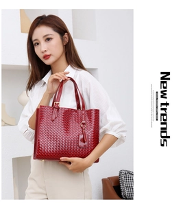 Detail of red woven texture handbag showing golden hardware and handle with chic white outfit