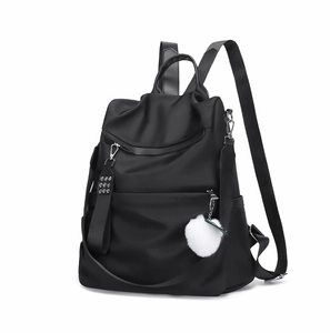 Détail d'un sac à dos en nylon noir étanche avec poches et porte-clés en peluche blanche