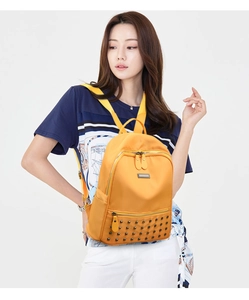 Detail view of bright yellow backpack with square rivets and premium nylon fabric texture