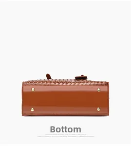 Detailed bottom view of brown woven tote bag featuring gold protective metal feet