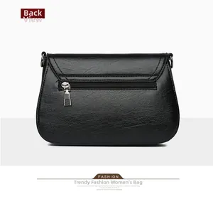 Detail view of the back zipper pocket on a black textured faux leather crossbody bag