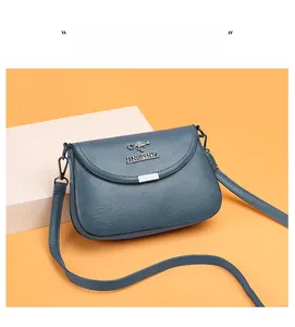 Detail of blue leather shoulder bag featuring a metal kangaroo logo and flap design