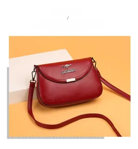 Detail of red leather crossbody bag featuring gold metal kangaroo logo and buckle
