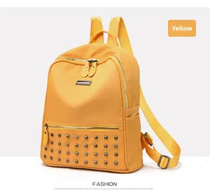 Detail of yellow fashion backpack showing silver square rivets and metal brand nameplate