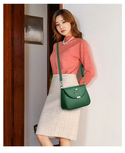 Detail showing emerald green leather crossbody bag with golden kangaroo logo on the flap