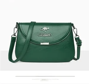 Detail of green textured faux leather crossbody bag with metal kangaroo logo and strap