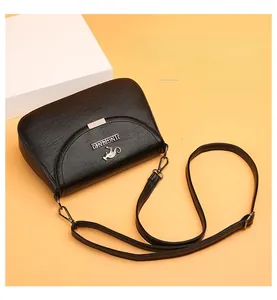 Detail of black crossbody bag with litchi texture and metal kangaroo logo on front