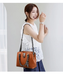 Detail of brown tote bag featuring snakeskin texture straps and gold-tone buckle