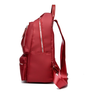 Sac à dos rouge en nylon pour femme avec plusieurs compartiments zippés et vue de profil