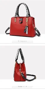 Detailed close-up of red PU leather tote bag with snakeskin pattern handles and heart charm