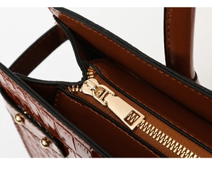 Detail view of gold zipper and brown crocodile pattern texture on the tote bag