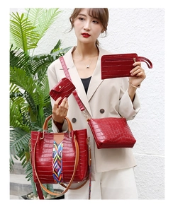 Detail of red crocodile texture handbag set featuring a colorful woven accent and straps
