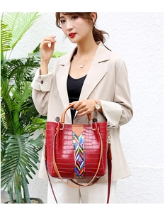 Detail of red croc-effect tote bag with rainbow woven strap and brown handles