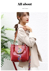 Detail of red crocodile textured handbag with colorful woven strap on a female model