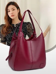 Detailed view of burgundy tote bag with pebble leather texture and embossed logo