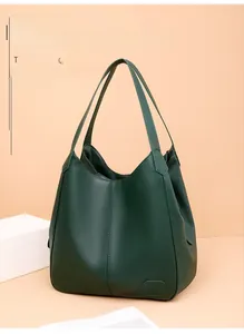 Detailed macro of dark green pebbled leather texture and embossed logo on tote bag
